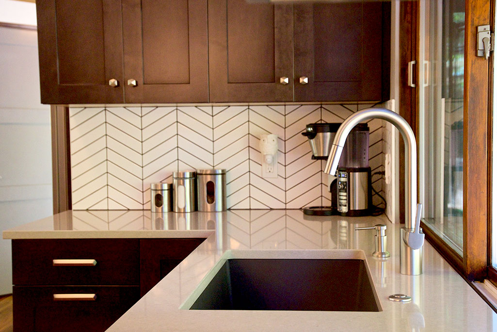 Stainless steel faucet and white herringbone backsplash tile