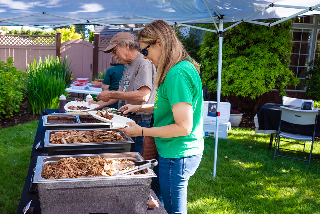 People serving themselves at outdoor buffet People serving themselves at outdoor buffet