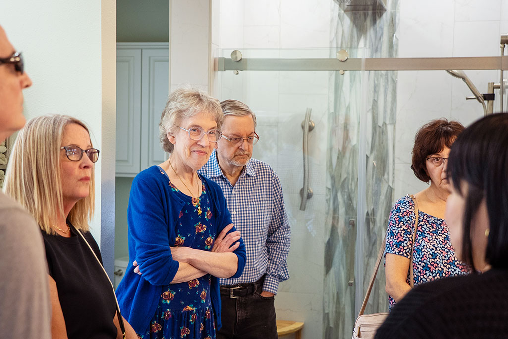 Group of adults gathered in bathroom showroom Group of adults gathered in bathroom showroom